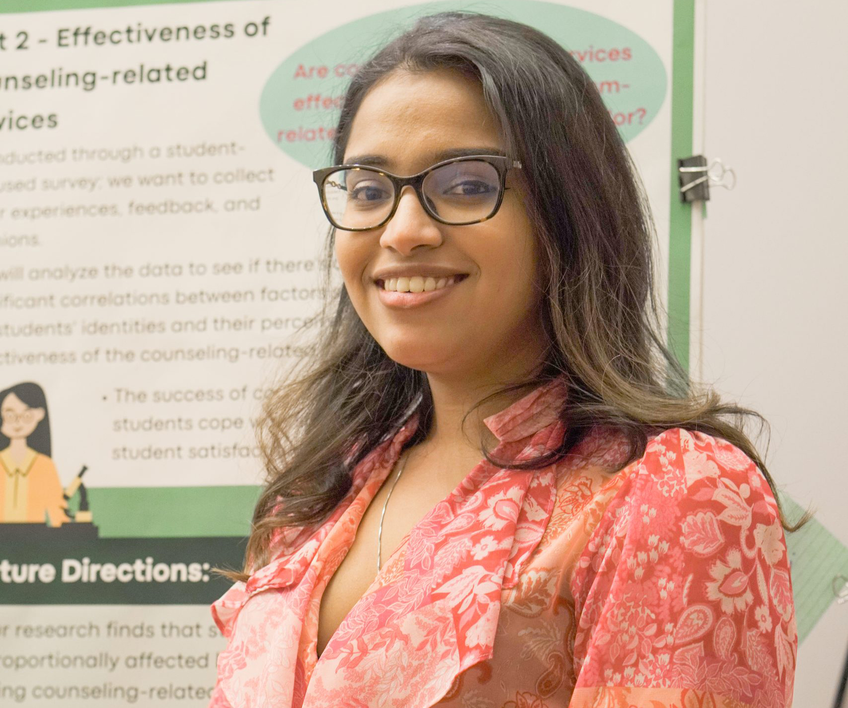 Mihika Sodani poses for a portrait in front of a research poster.