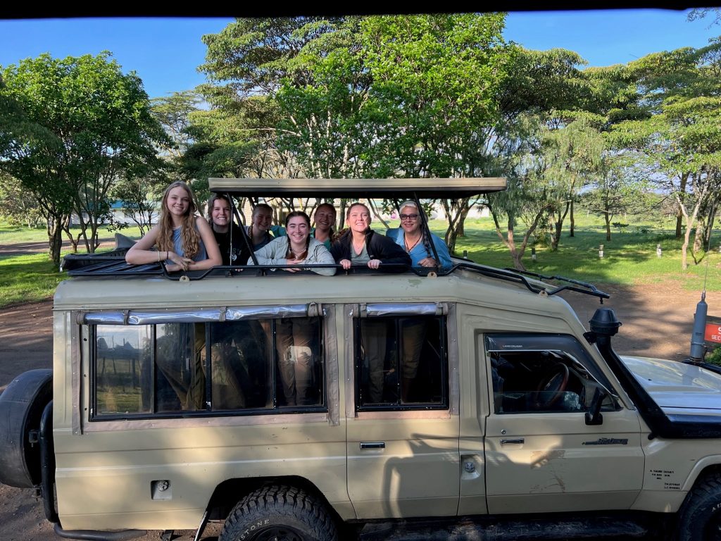 C S U students smile in a land cruiser with an open roof.