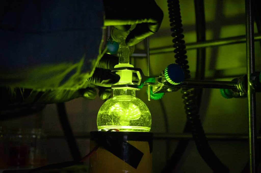 A beaker glows a bright green in a laboratory.