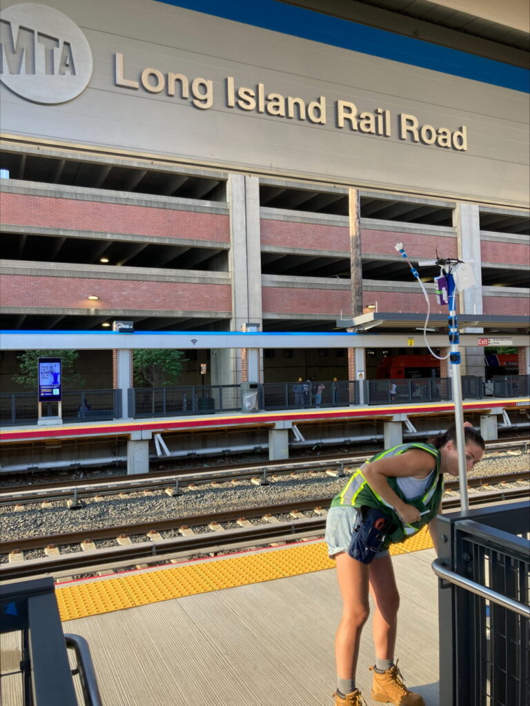 Someone wearing a high visibility vest checks a piece of equipment at a train station.