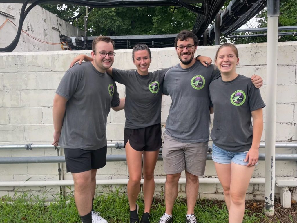 Four people stand together, smiling.